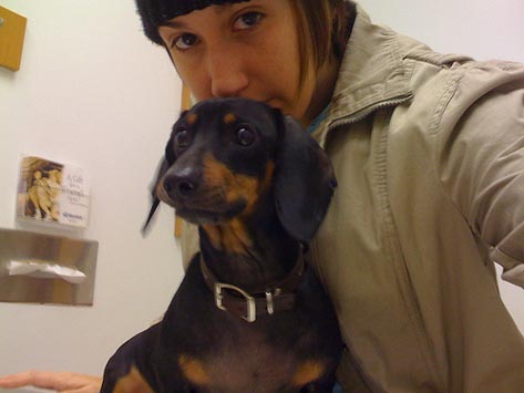 Woman and dacshund waiting at a veterinarian's office, poor prognosis in vet medicine, option in pet treatment